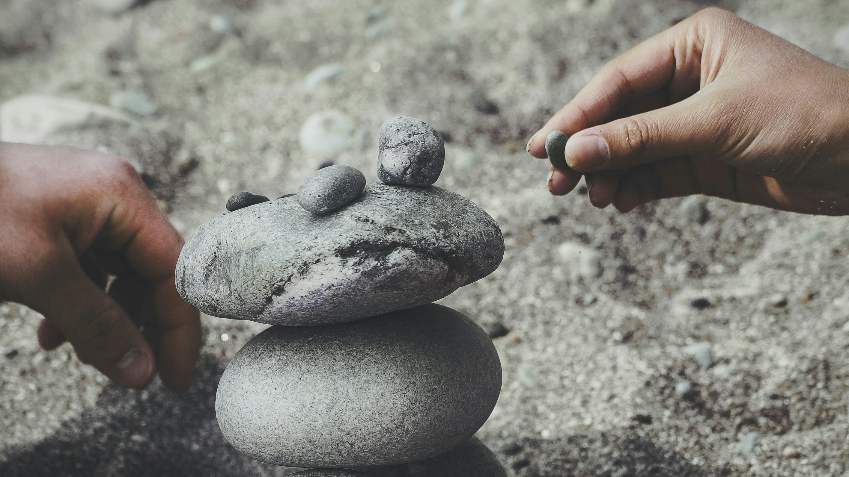 Two hands stacking rocks on top of each other